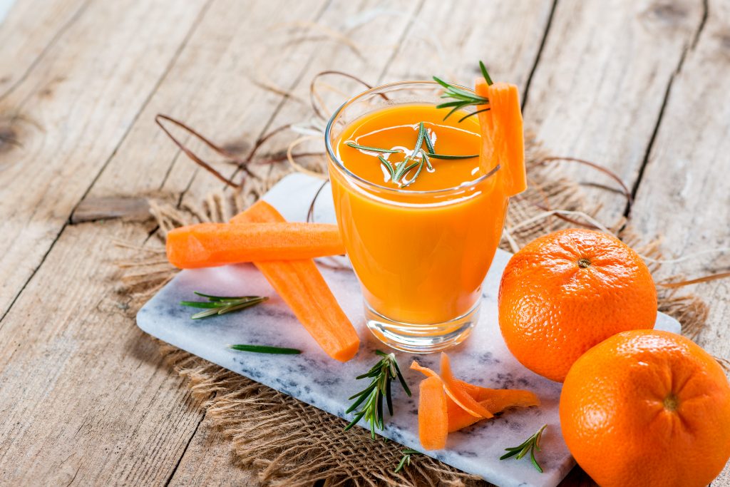 Succo di mandarini e carote in bicchiere di vetro con frutta e verdura