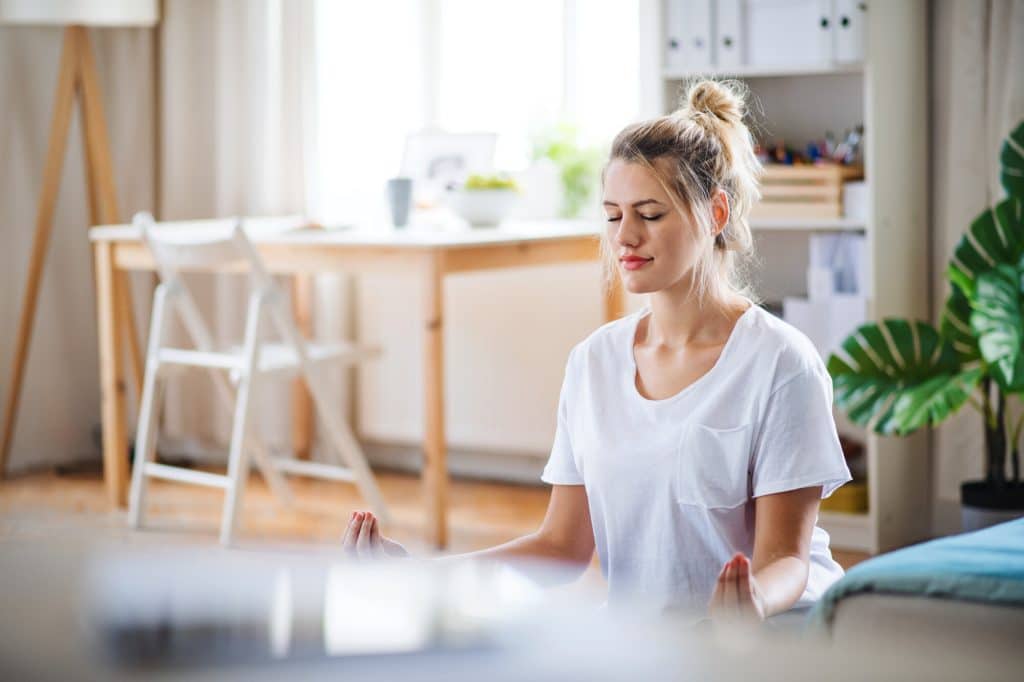 Donna che medita e fa yoga in casa.