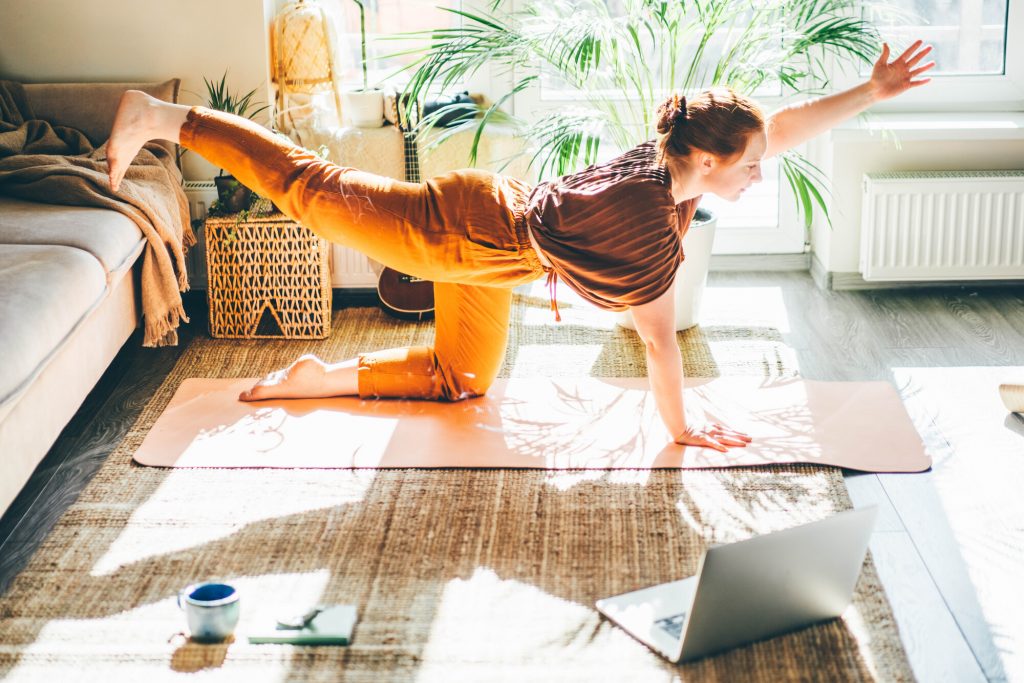 Donna fa yoga a casa seguendo un tutorial sul computer